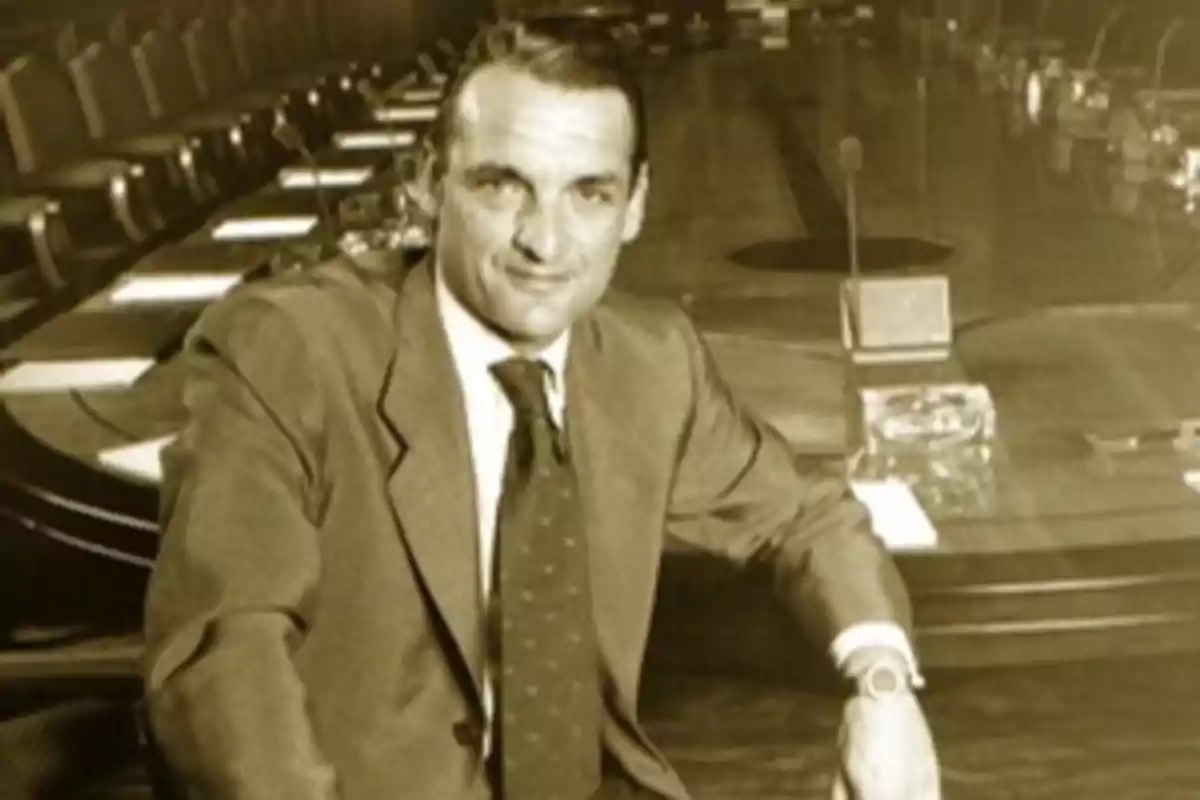 Un hombre de traje sentado en una mesa de conferencias.