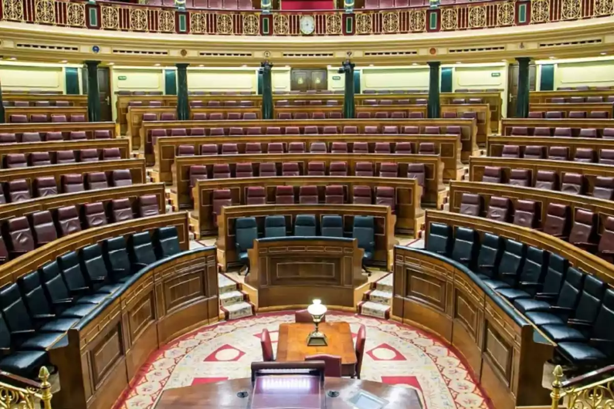 Vista del interior de un parlamento con asientos de cuero y detalles ornamentales en madera.