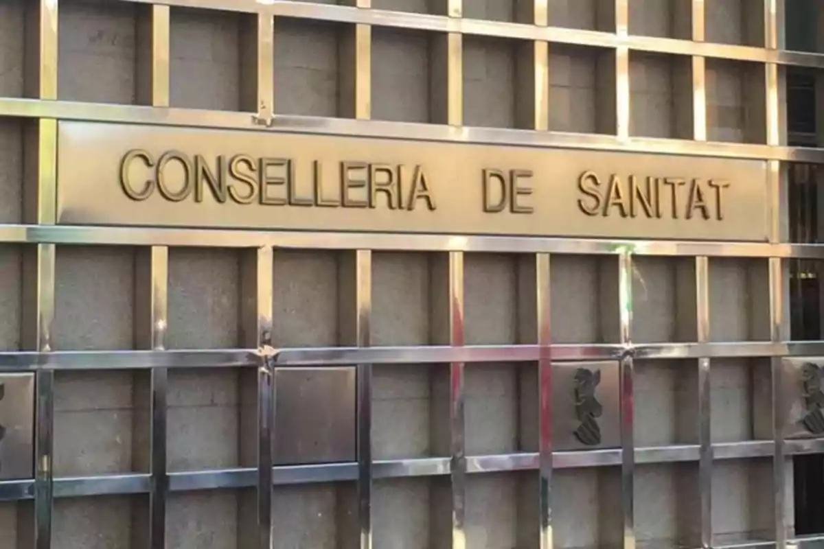 Un cartel metálico que dice "Conselleria de Sanitat" en una pared.