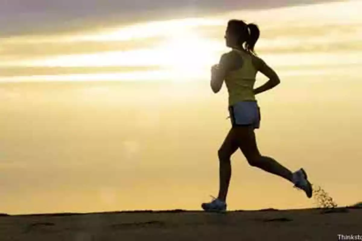 Persona corriendo al amanecer en un paisaje despejado.