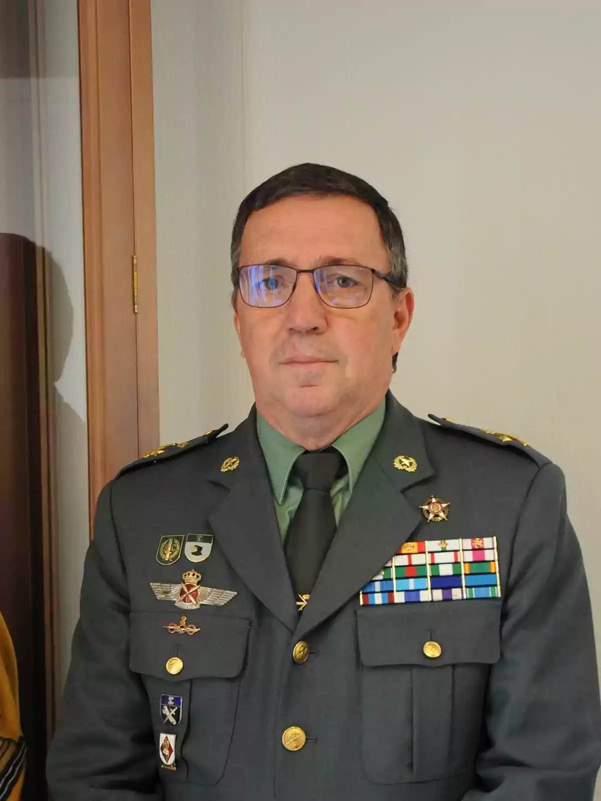 Un oficial militar con uniforme verde y varias insignias y medallas.