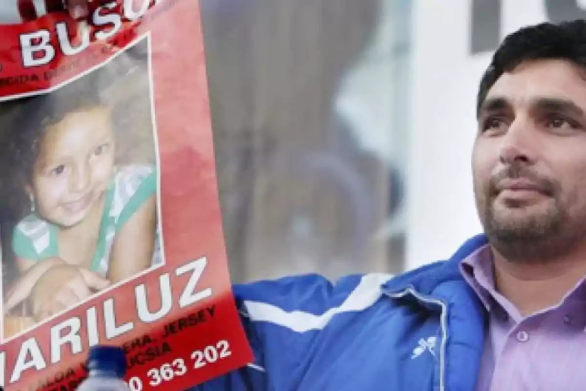 Un hombre sostiene un cartel de búsqueda con la foto de una niña sonriente.