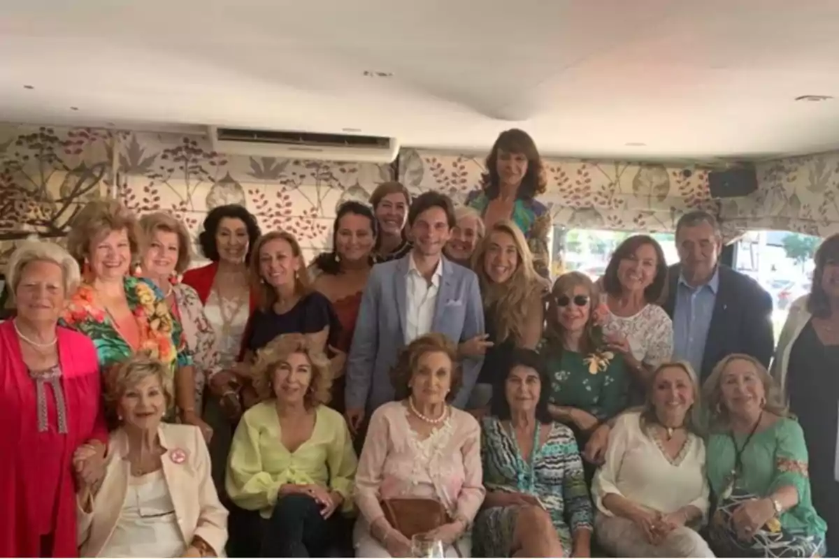 Un grupo de personas posando juntas en un ambiente interior con decoración floral en las paredes.