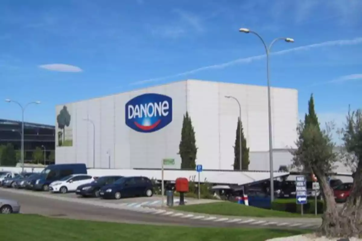 Fábrica de Danone con estacionamiento y varios autos al frente en un día soleado Fábrica de Danone con estacionamiento y varios autos al frente en un día soleado