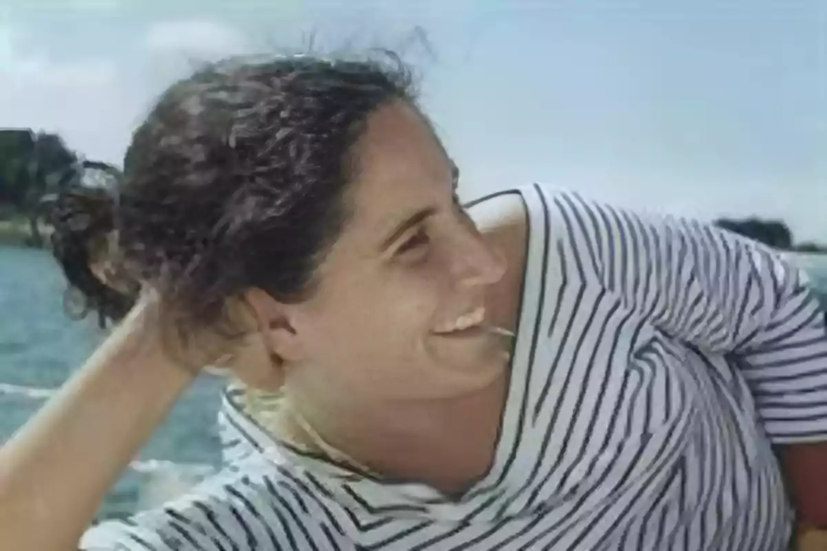 Mujer sonriente con camiseta de rayas recostada al aire libre junto al agua Mujer sonriente con camiseta de rayas recostada al aire libre junto al agua