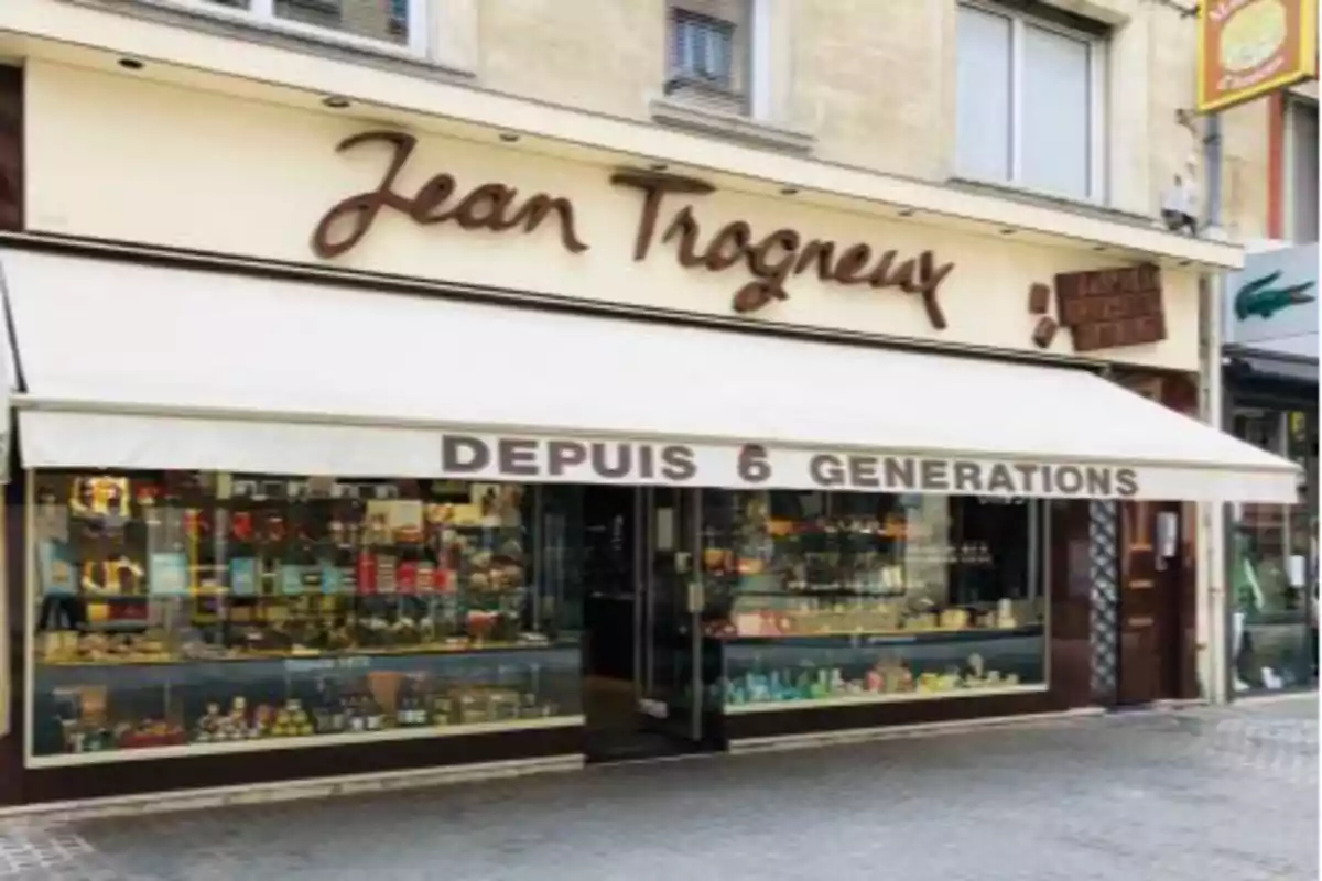 Fachada de la tienda Jean Trogneux con un toldo blanco que dice Fachada de la tienda Jean Trogneux con un toldo blanco que dice