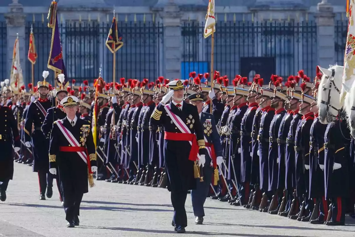 Desfile militar con oficiales uniformados marchando y saludando frente a una formación de soldados en un entorno ceremonial.