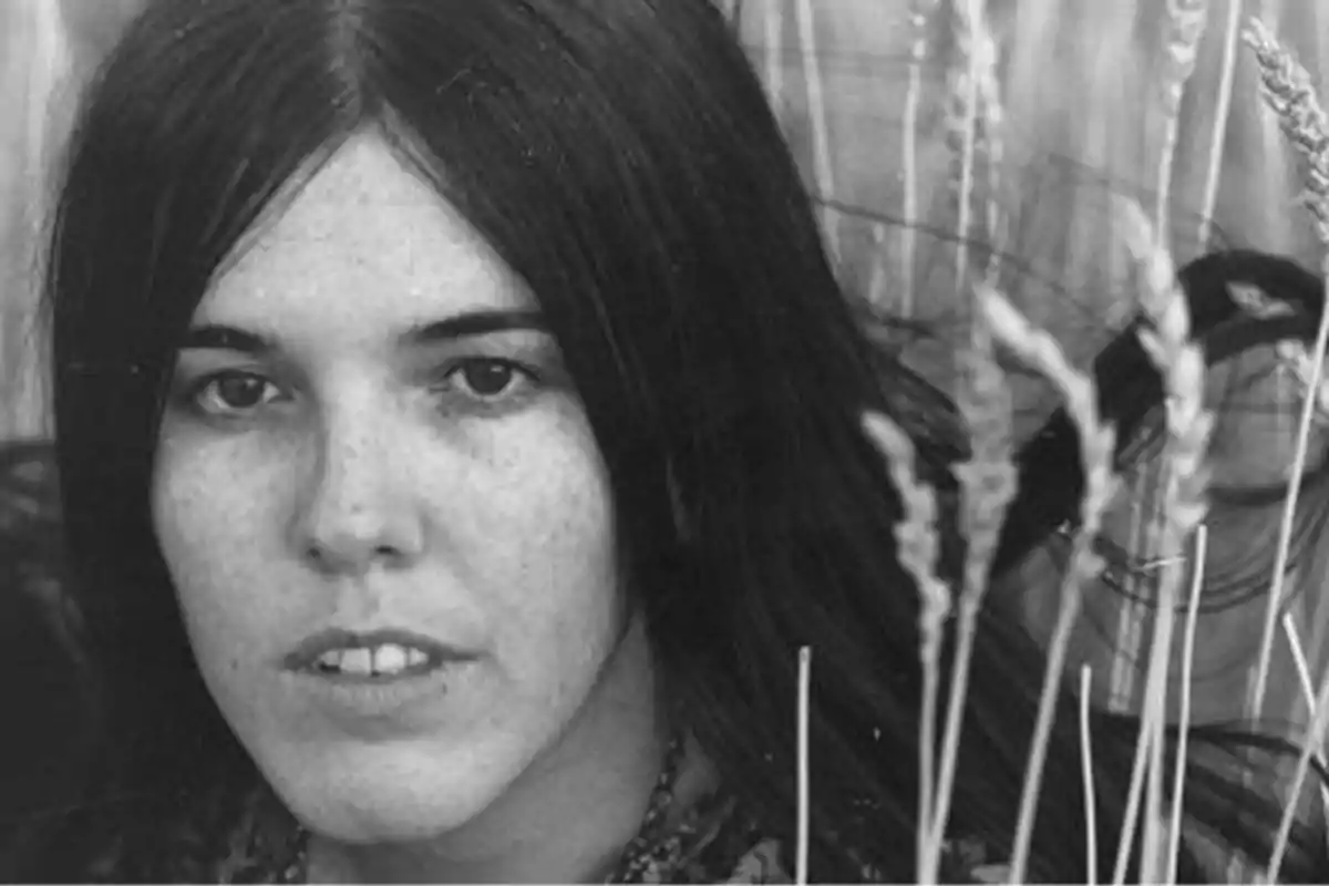 Mujer joven con cabello largo y oscuro en un campo de trigo.