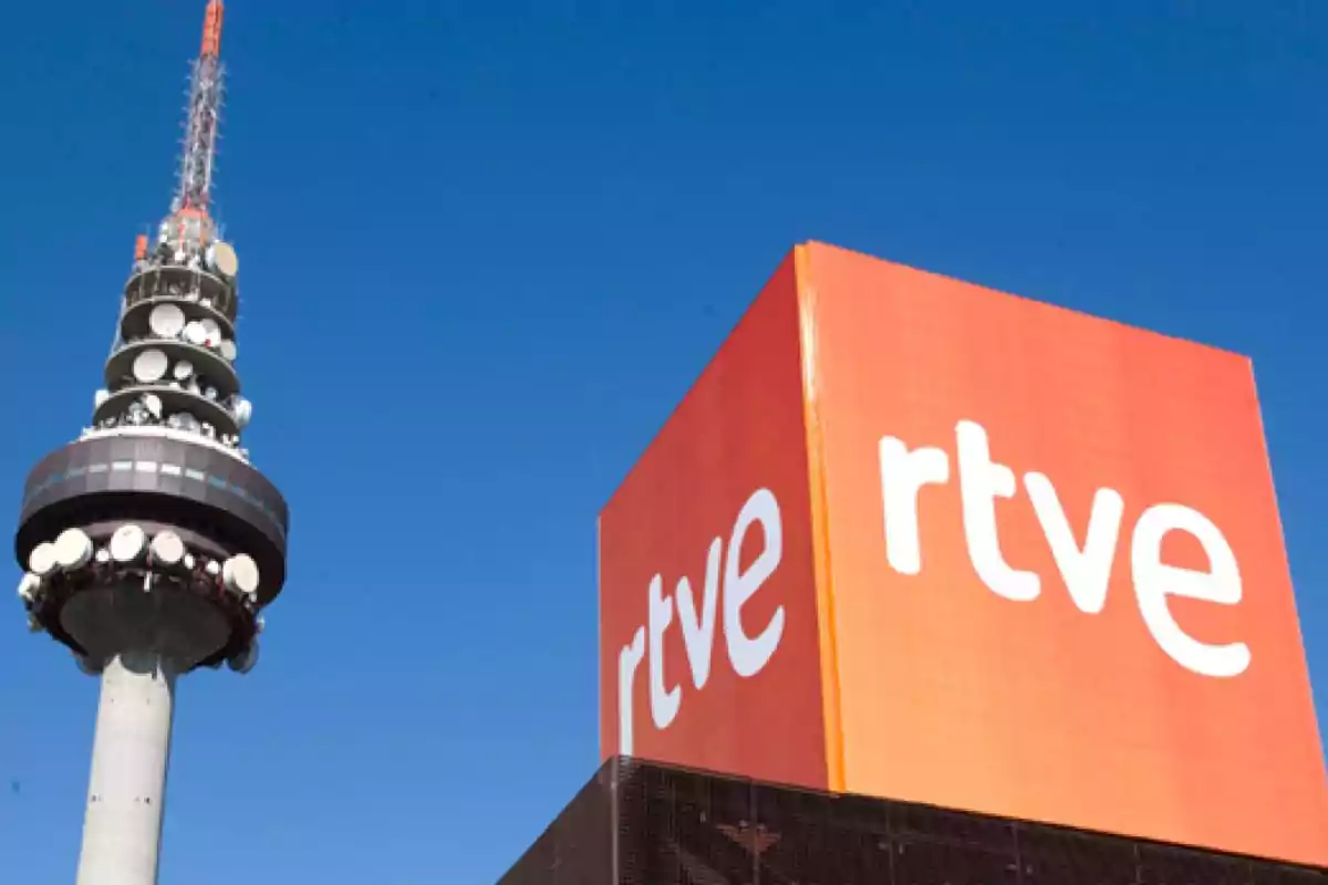 Edificio de RTVE junto a una torre de telecomunicaciones bajo un cielo azul Edificio de RTVE junto a una torre de telecomunicaciones bajo un cielo azul