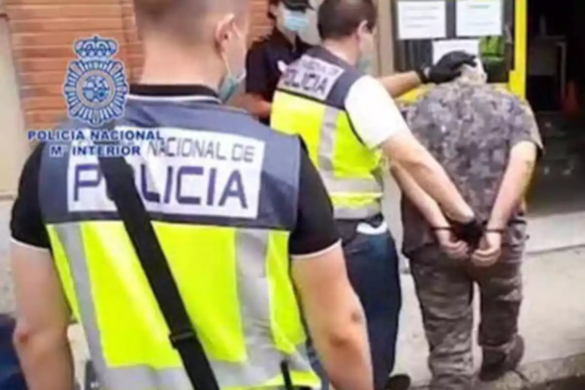 Policías nacionales arrestando a un hombre esposado.