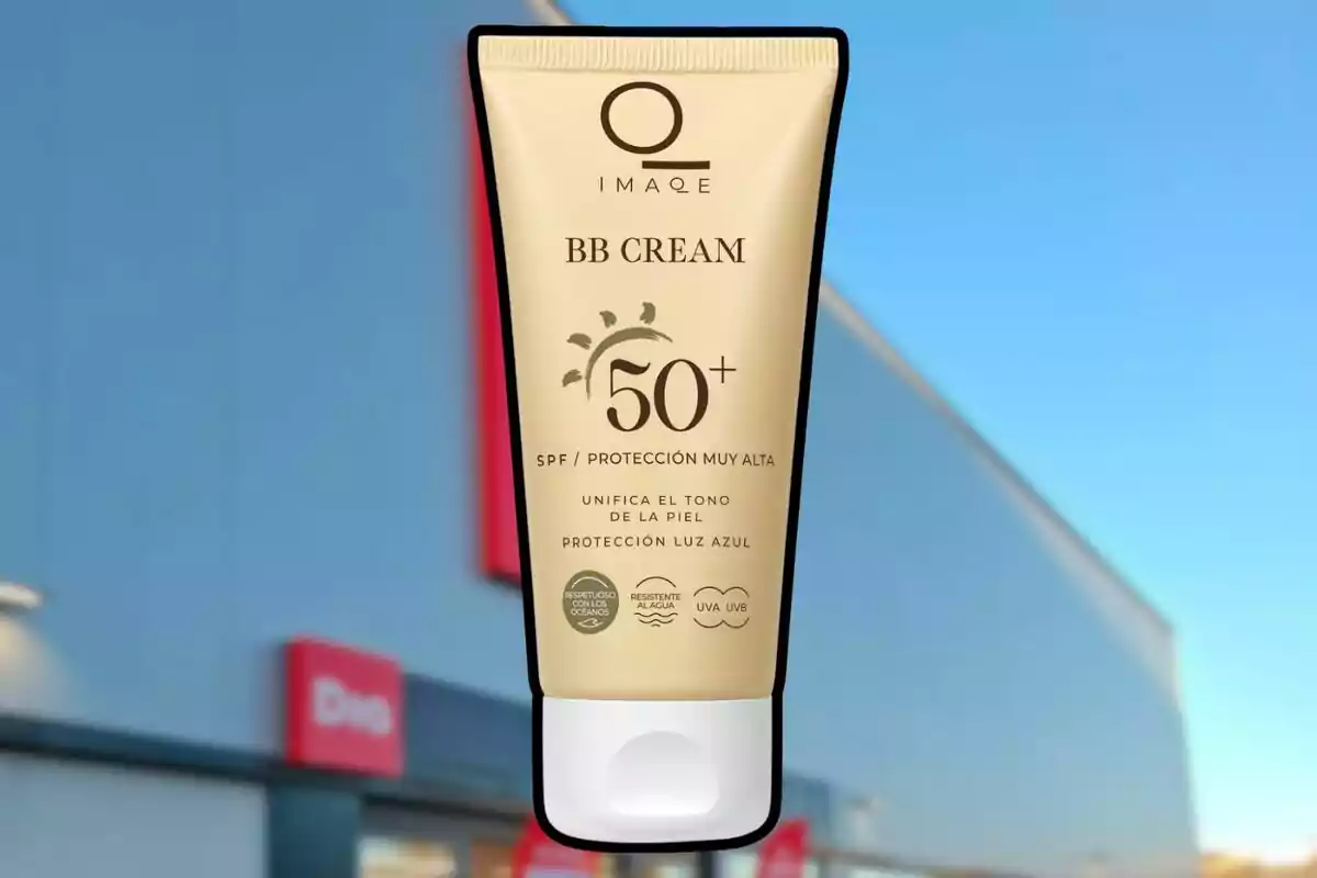 Envase de BB Cream con protección solar SPF 50 más suspendido frente a una tienda con fachada azul y letreros rojos. Envase de BB Cream con protección solar SPF 50 más suspendido frente a una tienda con fachada azul y letreros rojos.