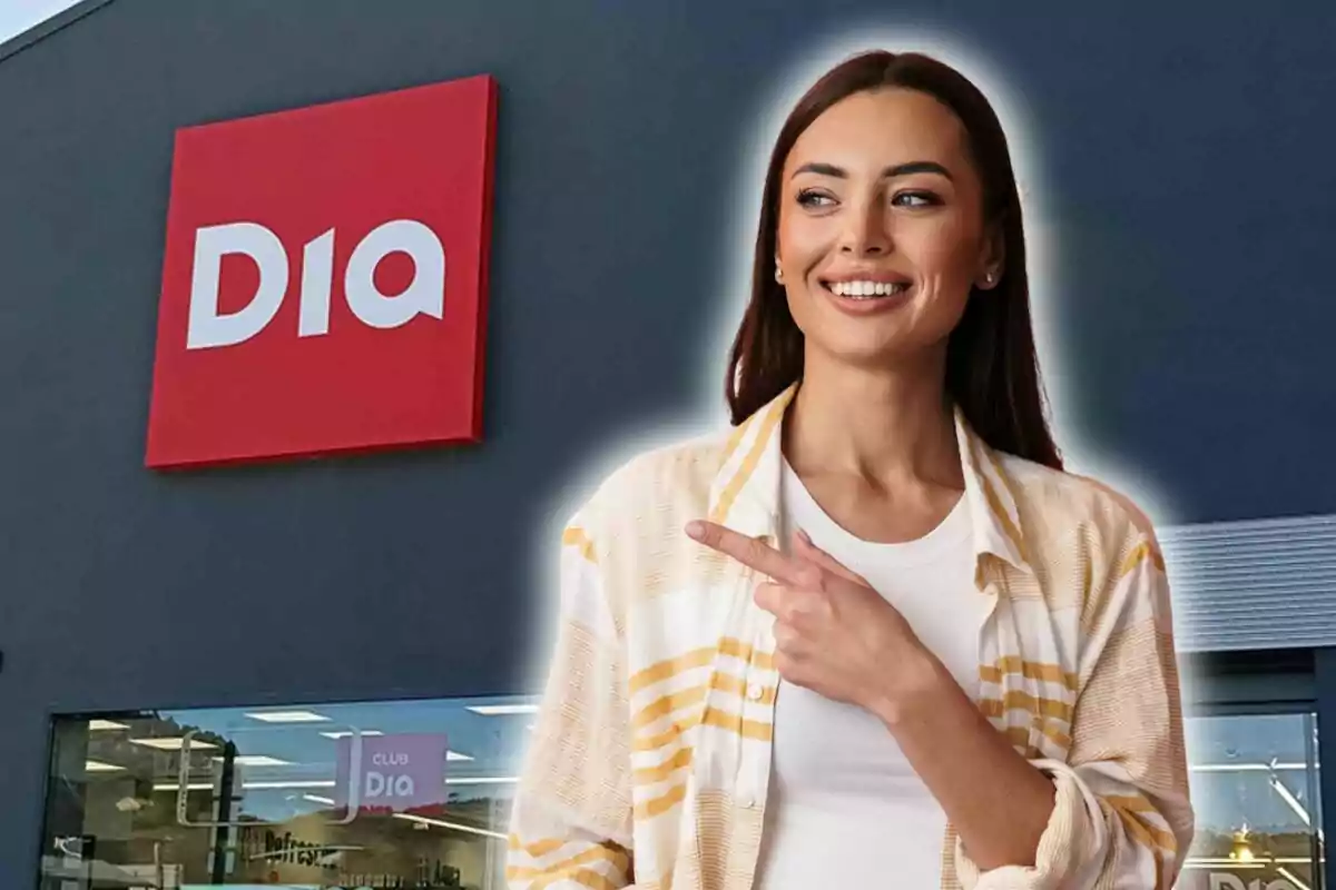Una persona sonriente señala hacia el logotipo de una tienda Dia en el fondo.