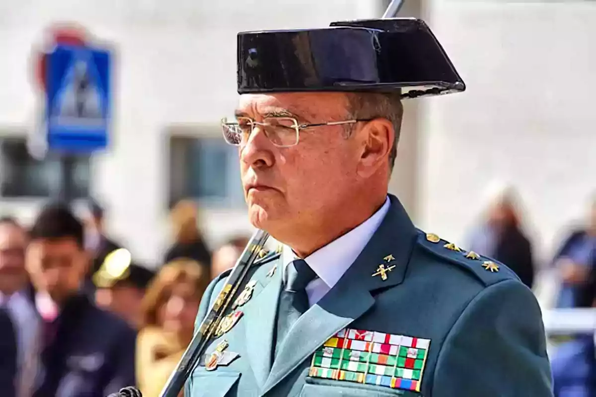 Un oficial de la Guardia Civil en uniforme con medallas y un sombrero tradicional durante un evento al aire libre.