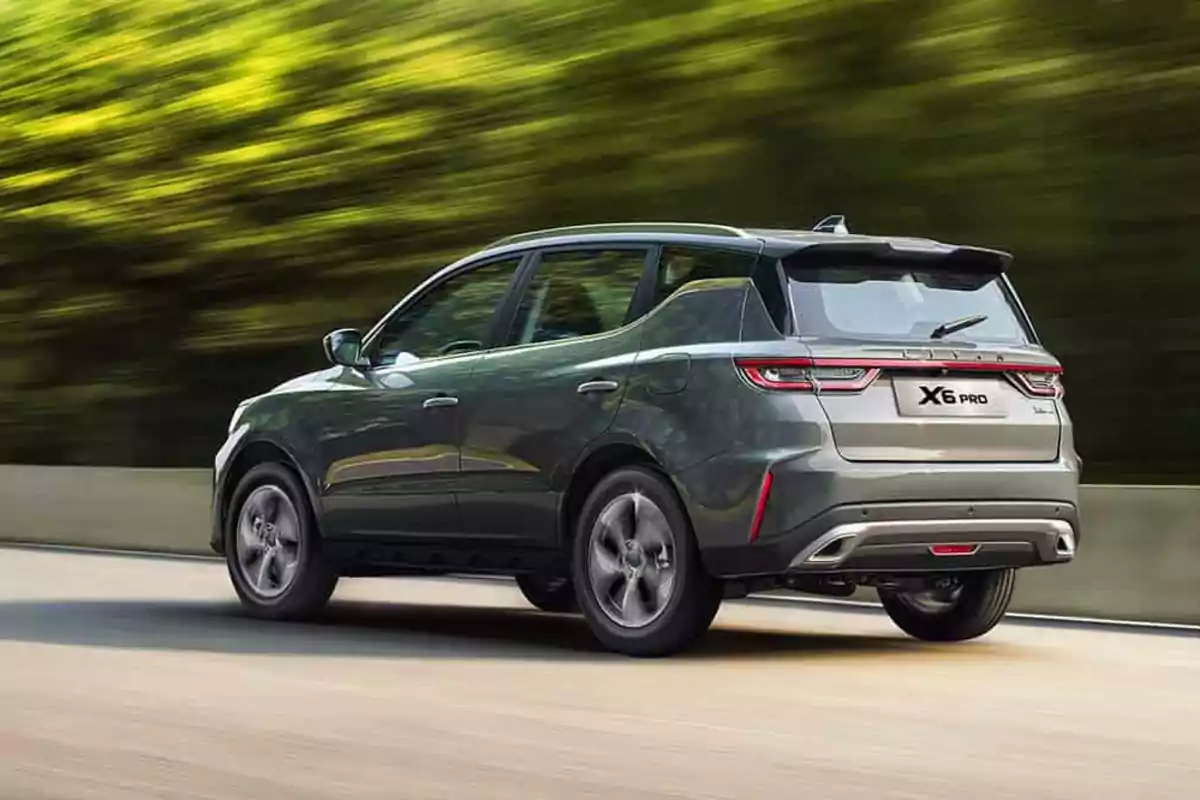 SUV gris X6 Pro conduciendo por una carretera con fondo de árboles desenfocados
