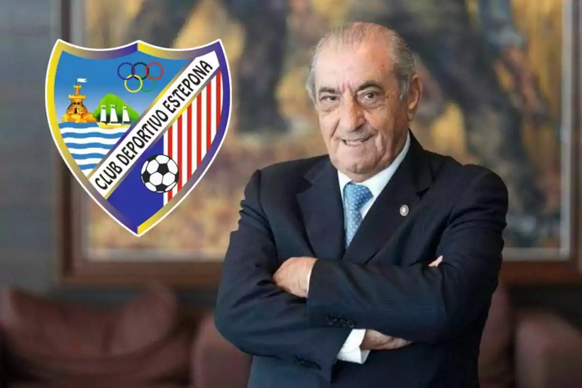 Hombre mayor de traje con los brazos cruzados y el escudo del Club Deportivo Estepona a su lado
