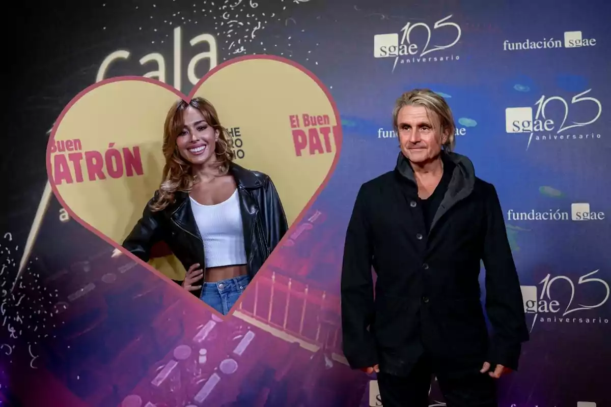 Dos personas posan en un evento, una mujer sonriente dentro de un marco en forma de corazón y un hombre con chaqueta negra frente a un fondo con logotipos de SGAE y Fundación SGAE.