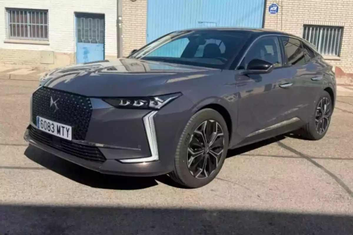 Un coche gris estacionado en una calle frente a un edificio con puertas azules.