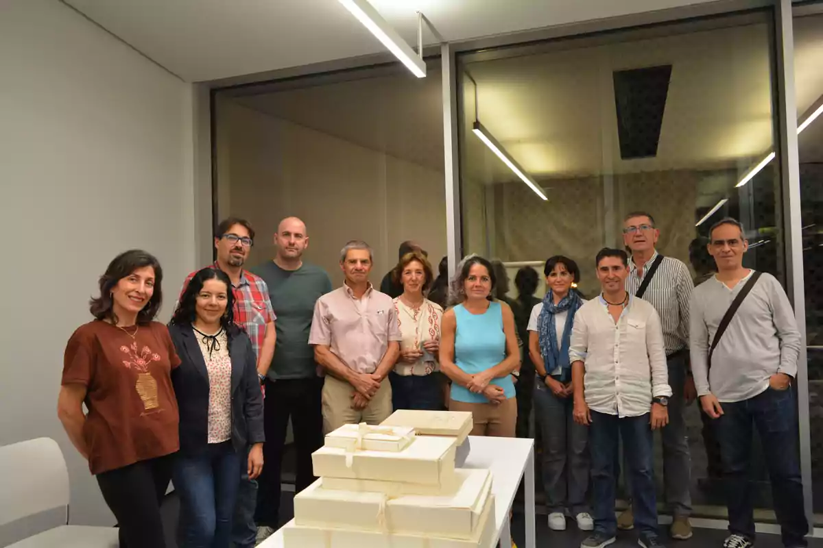 Un grupo de personas posando juntas en una sala con cajas apiladas sobre una mesa.