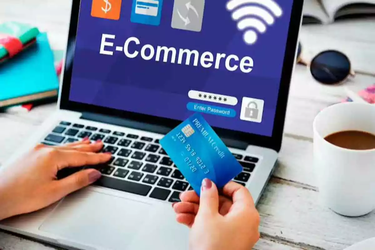 Persona sosteniendo una tarjeta de crédito frente a una computadora portátil con una pantalla que muestra "E-Commerce".