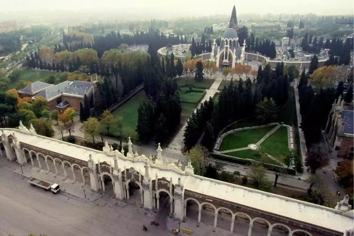 Vista aérea de un cementerio con una entrada monumental y jardines rodeados de árboles.