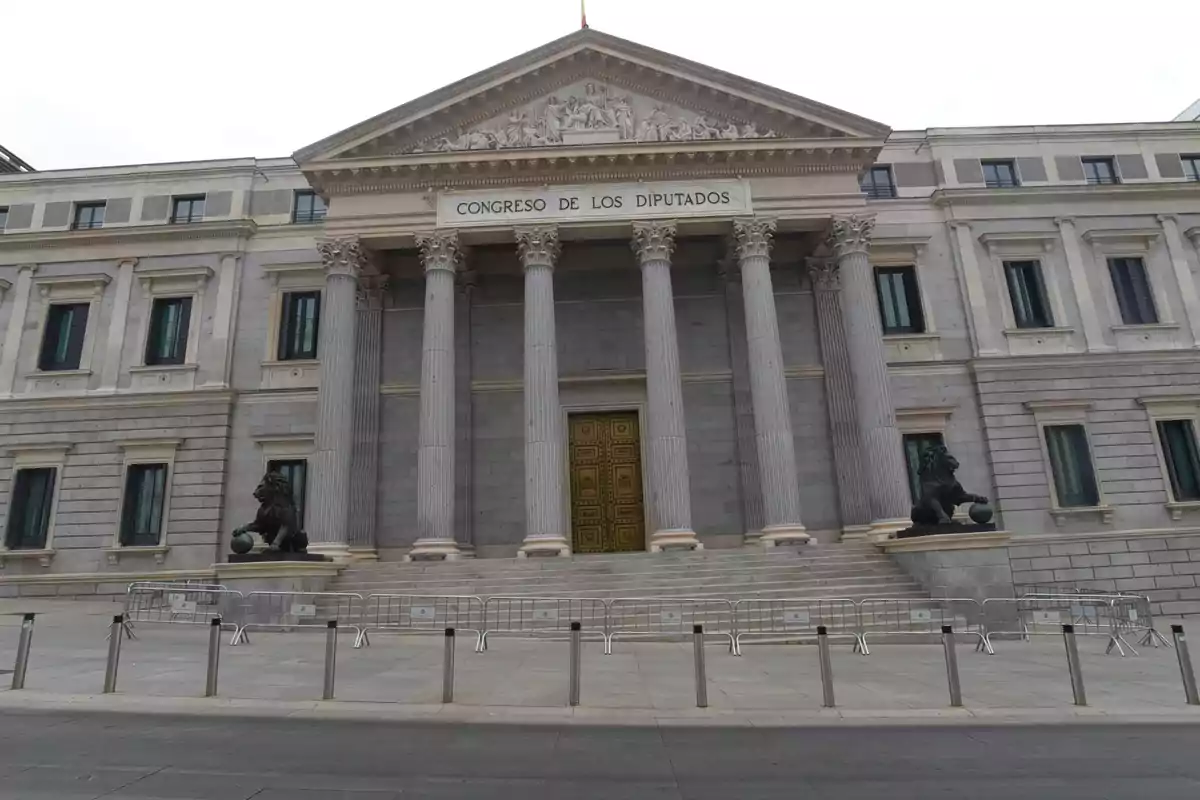 Fachada del Congreso de los Diputados en Madrid, España, con columnas y estatuas de leones a ambos lados de la entrada principal.