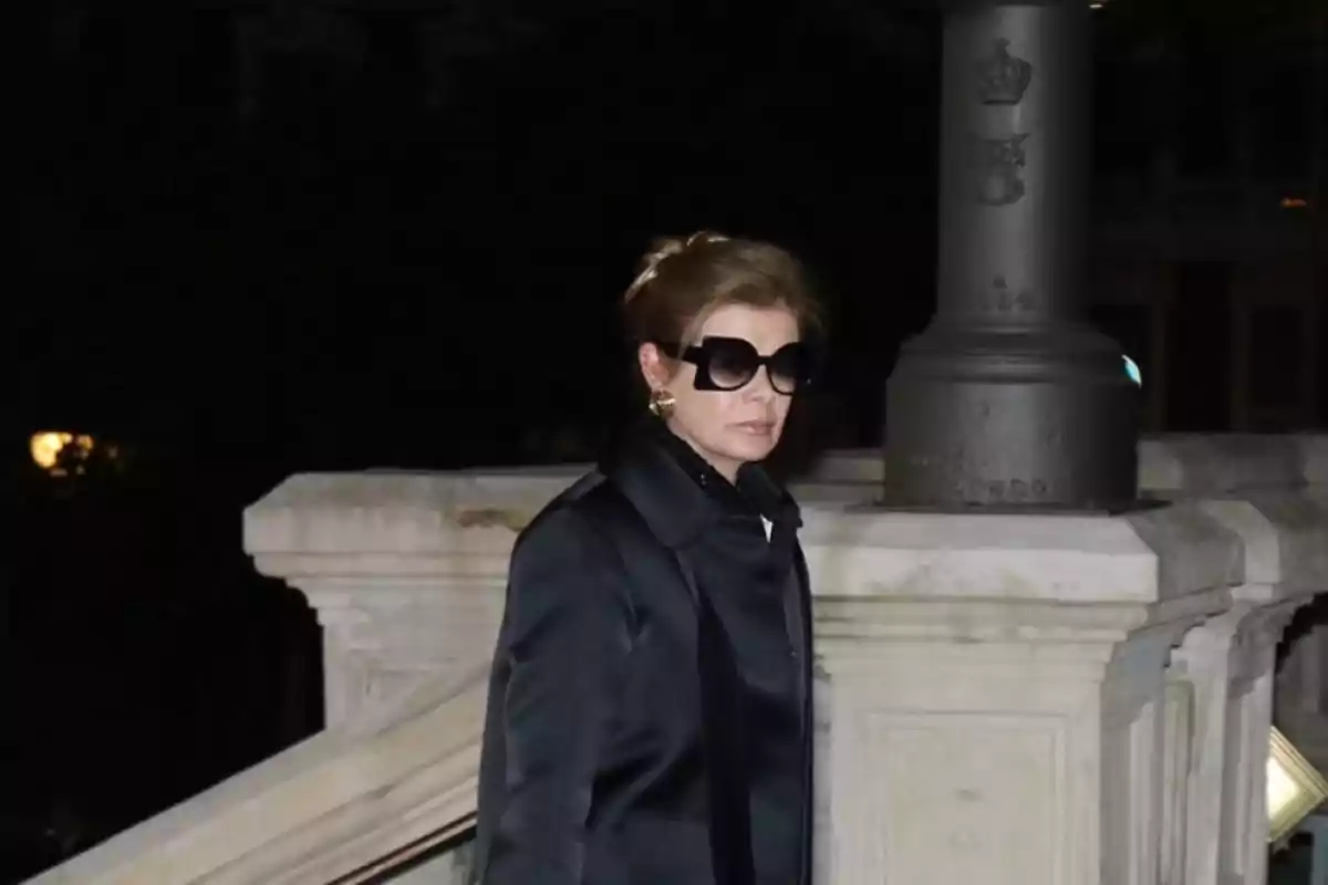 Mujer con gafas de sol grandes y abrigo oscuro caminando por unas escaleras de piedra en la noche Mujer con gafas de sol grandes y abrigo oscuro caminando por unas escaleras de piedra en la noche