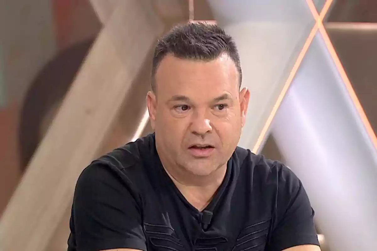 Un hombre con camiseta negra en un estudio de televisión.