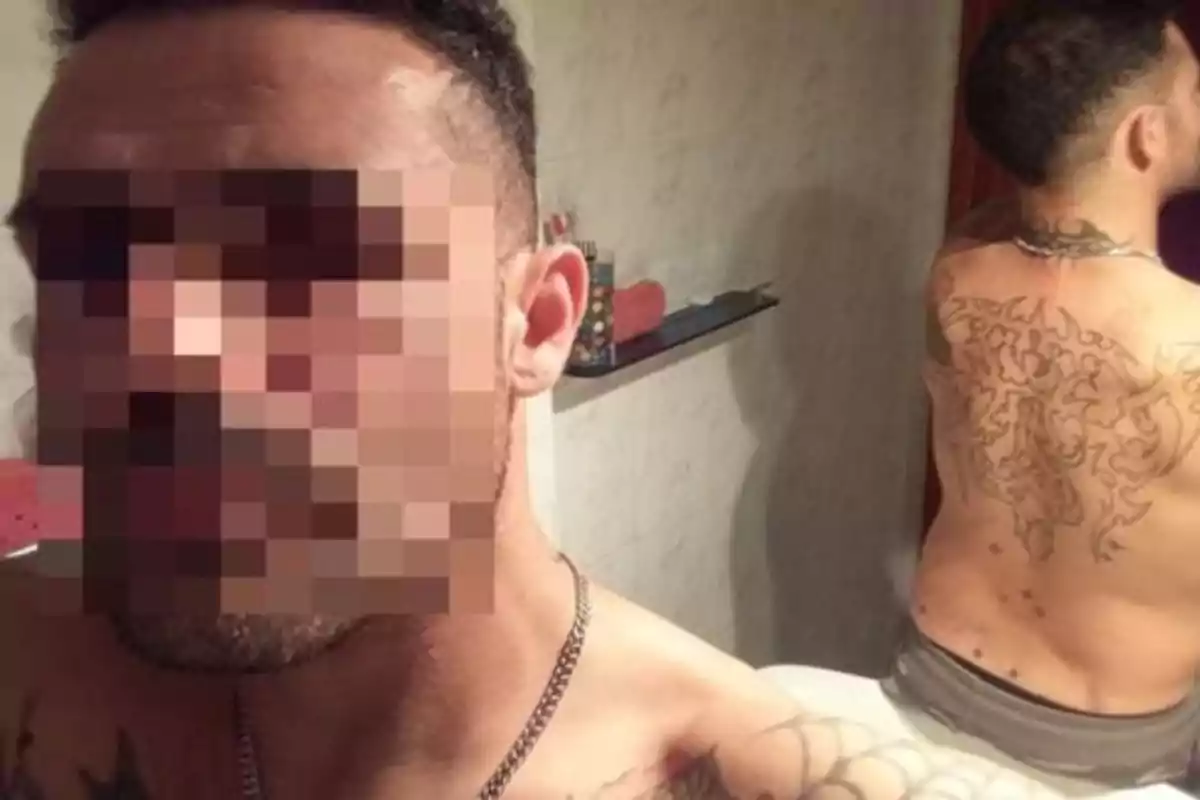 Hombre con el rostro pixelado mostrando un tatuaje grande en la espalda en un baño.