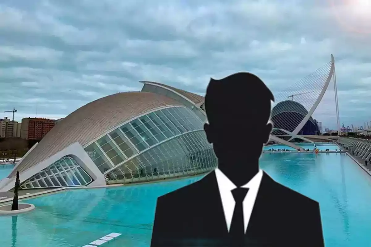 Silueta de una persona con traje frente a la Ciudad de las Artes y las Ciencias en Valencia con cielo nublado