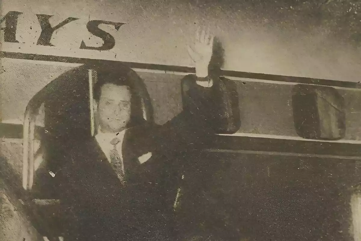 Hombre con traje saludando con la mano mientras está de pie en la puerta de un avión antiguo Hombre con traje saludando con la mano mientras está de pie en la puerta de un avión antiguo