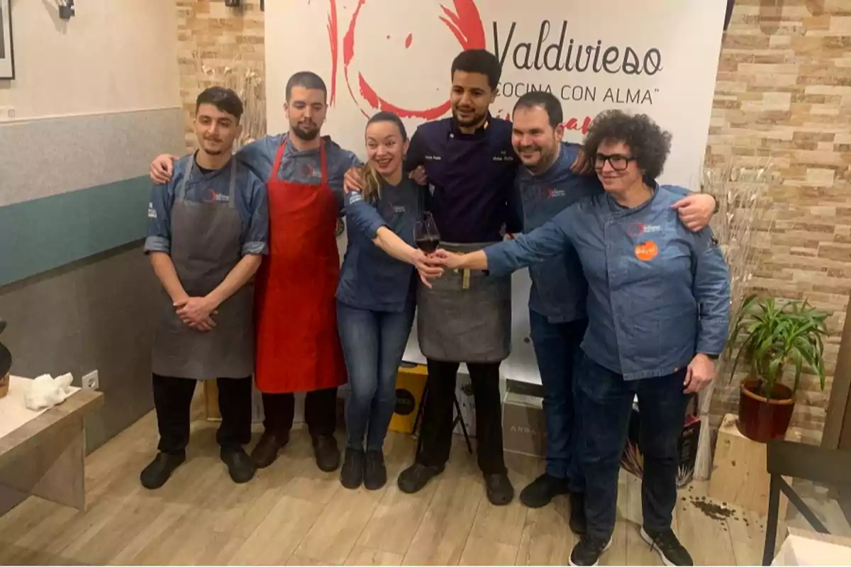 Un grupo de personas con delantales posando juntas en un restaurante llamado Valdivieso.