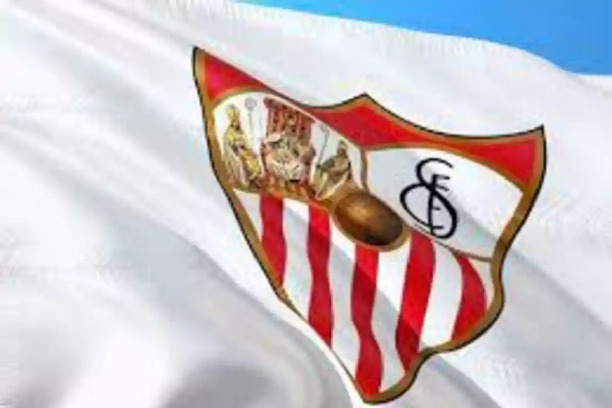 Bandera ondeante con el escudo del Sevilla FC sobre un fondo azul claro.