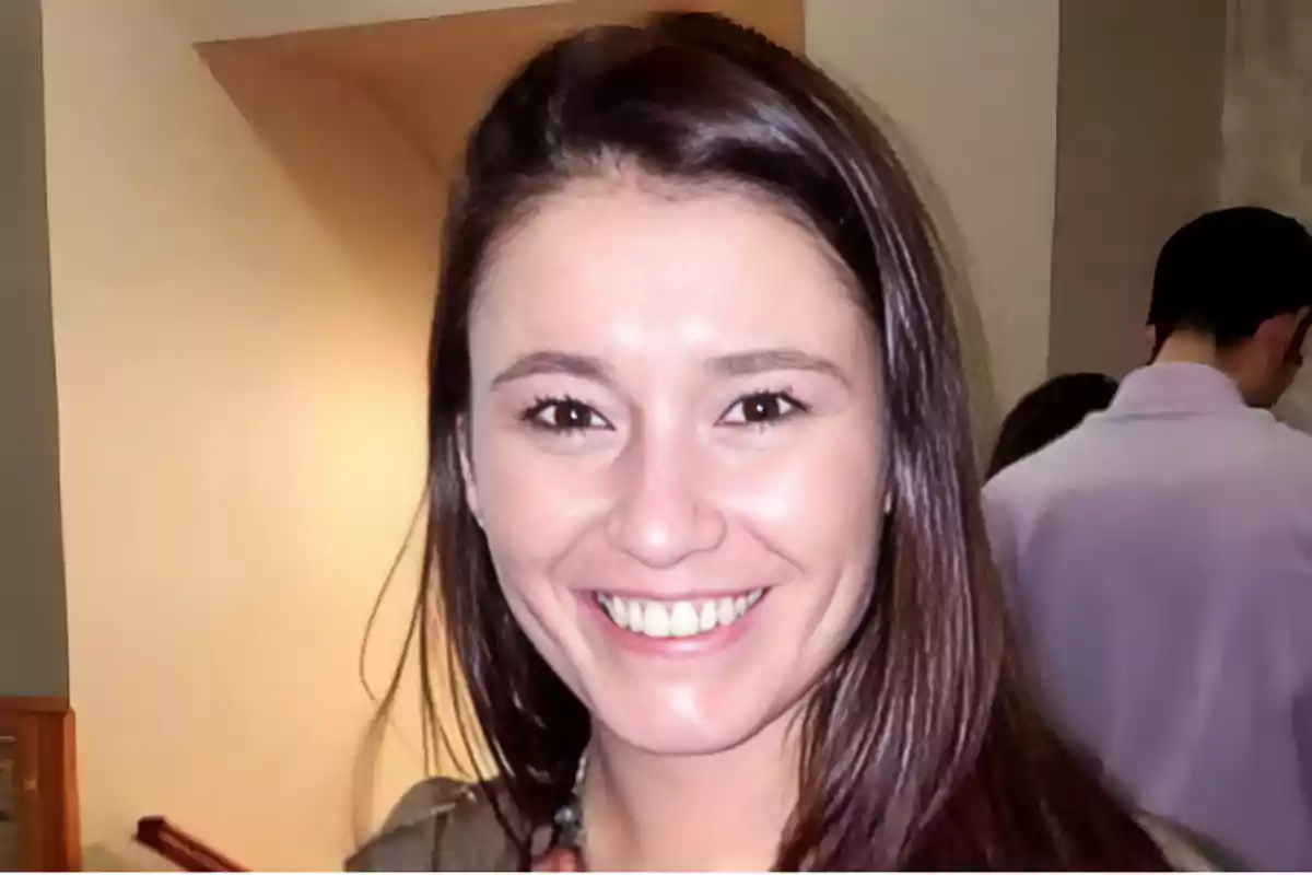 Una mujer sonriente con cabello oscuro en un ambiente interior.