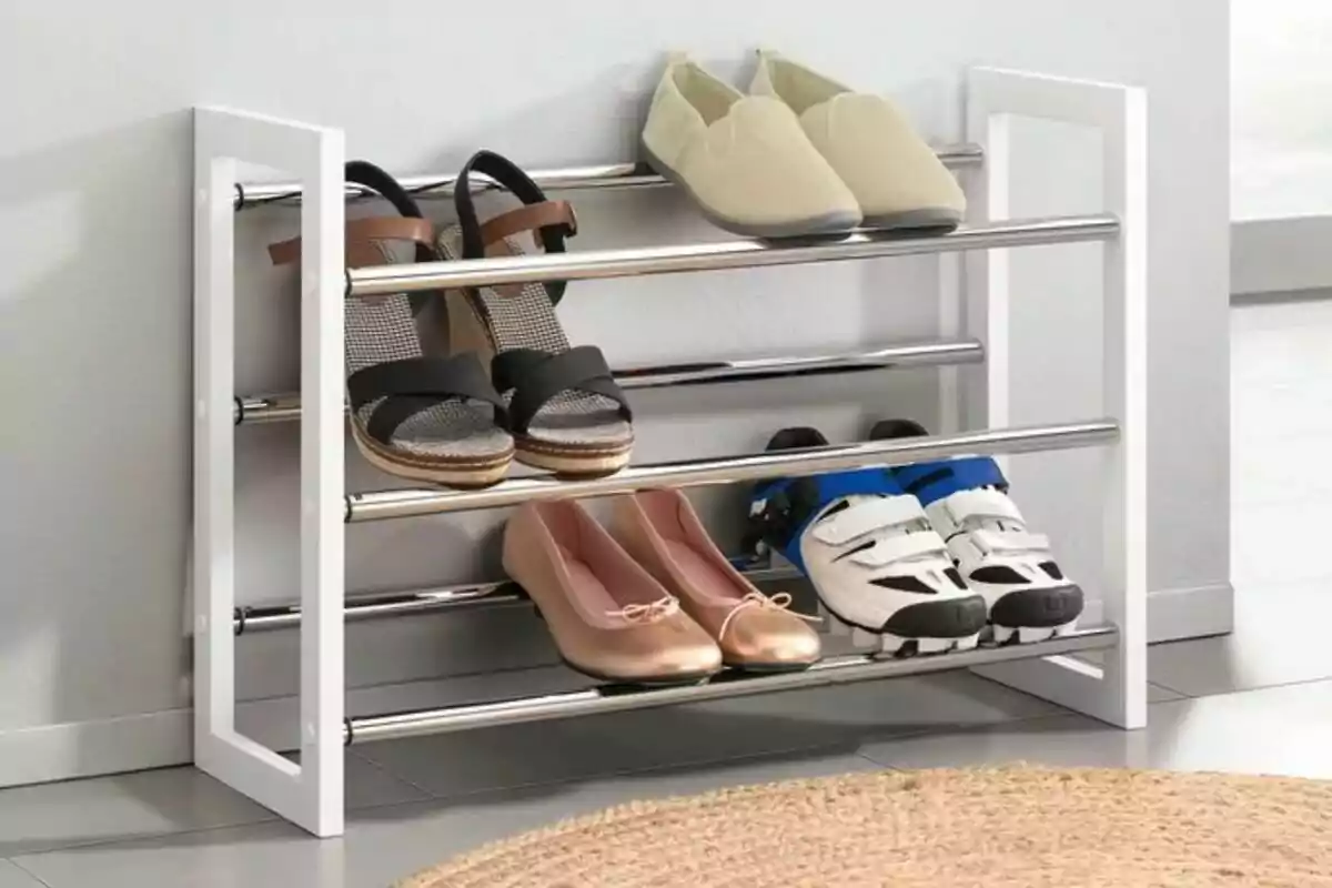 Zapatero metálico blanco de Lidl con varios pares de zapatos organizados en diferentes niveles sobre un piso de cerámica junto a una alfombra redonda. Zapatero metálico blanco de Lidl con varios pares de zapatos organizados en diferentes niveles sobre un piso de cerámica junto a una alfombra redonda.