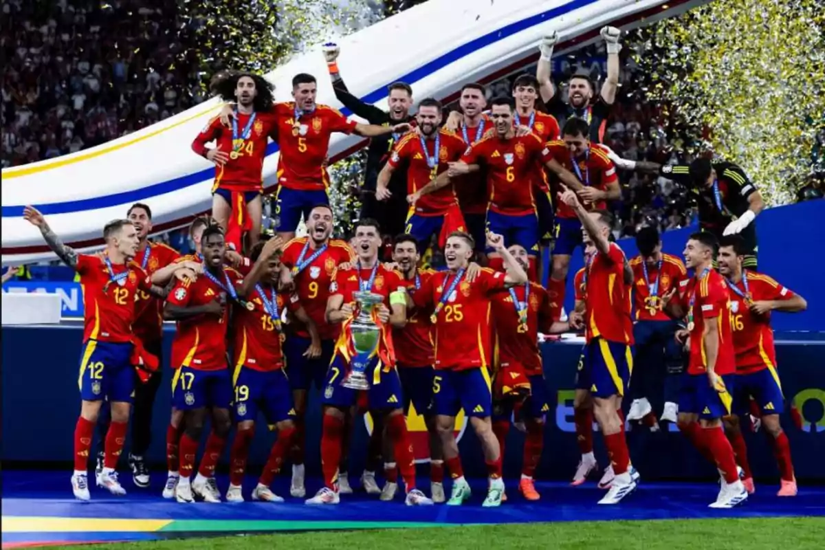 Jugadores de la selección española de fútbol celebrando con un trofeo y medallas, con confeti dorado en el fondo.