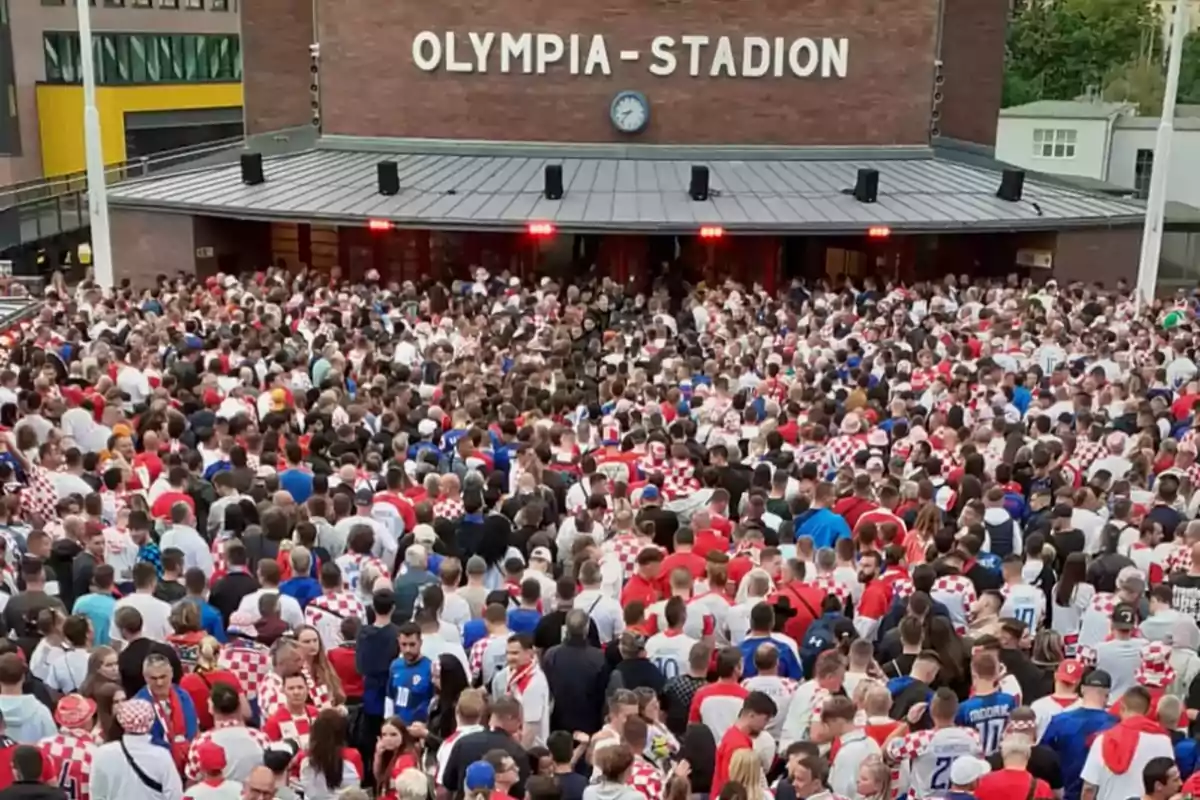Una multitud de personas con camisetas de fútbol se reúne frente a la entrada del Olympia-Stadion.