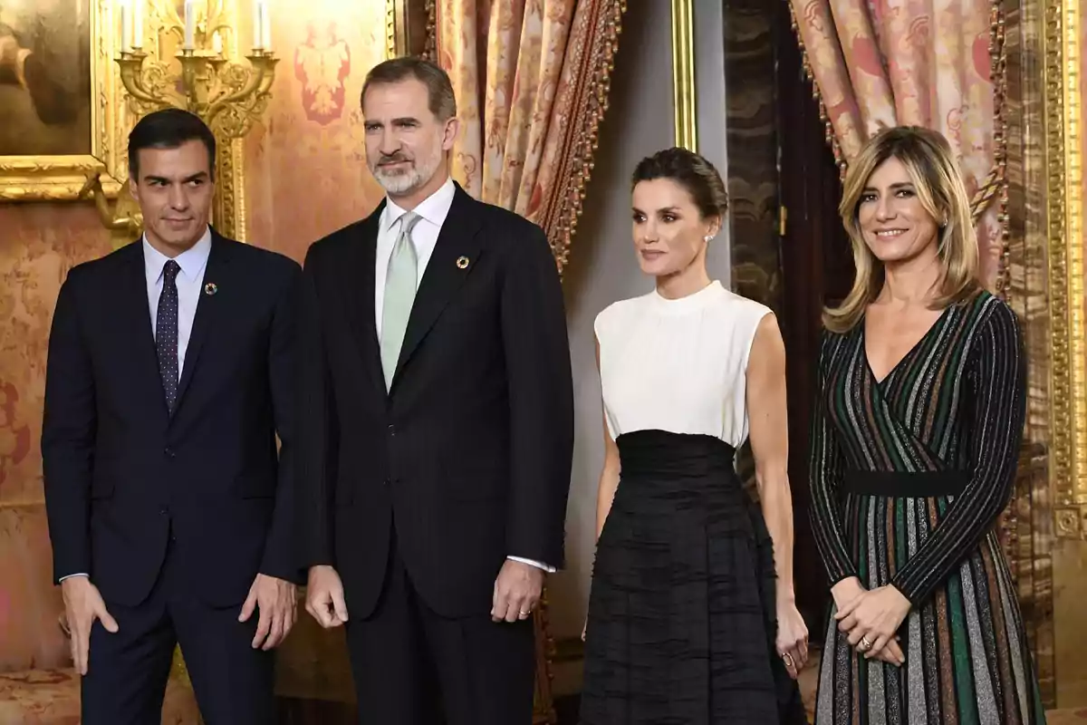 Cuatro personas posan elegantemente vestidas en un entorno decorado con cortinas y candelabros dorados.