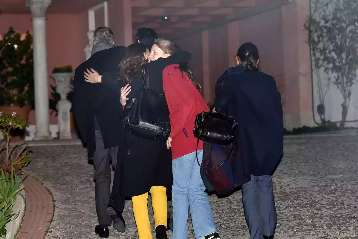 Un grupo de personas camina por un camino de piedra mientras dos de ellas se abrazan. Un grupo de personas camina por un camino de piedra mientras dos de ellas se abrazan.