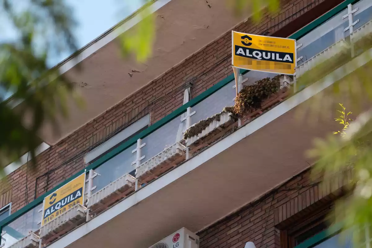 Un edificio de apartamentos con letreros de "Se Alquila" en los balcones.