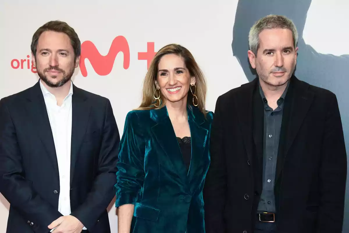 Tres personas posan juntas en un evento con un fondo que incluye el logo de una plataforma de streaming.