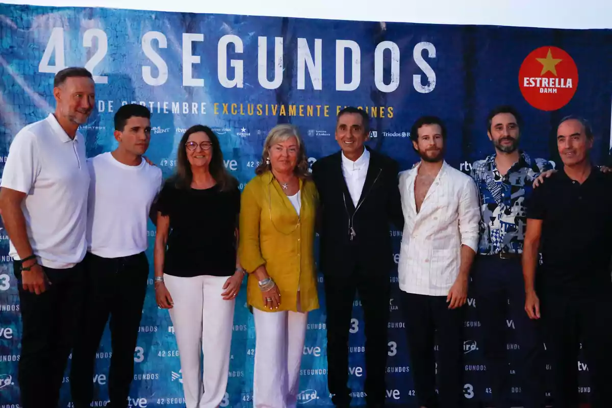 Un grupo de personas posando frente a un cartel promocional de la película 