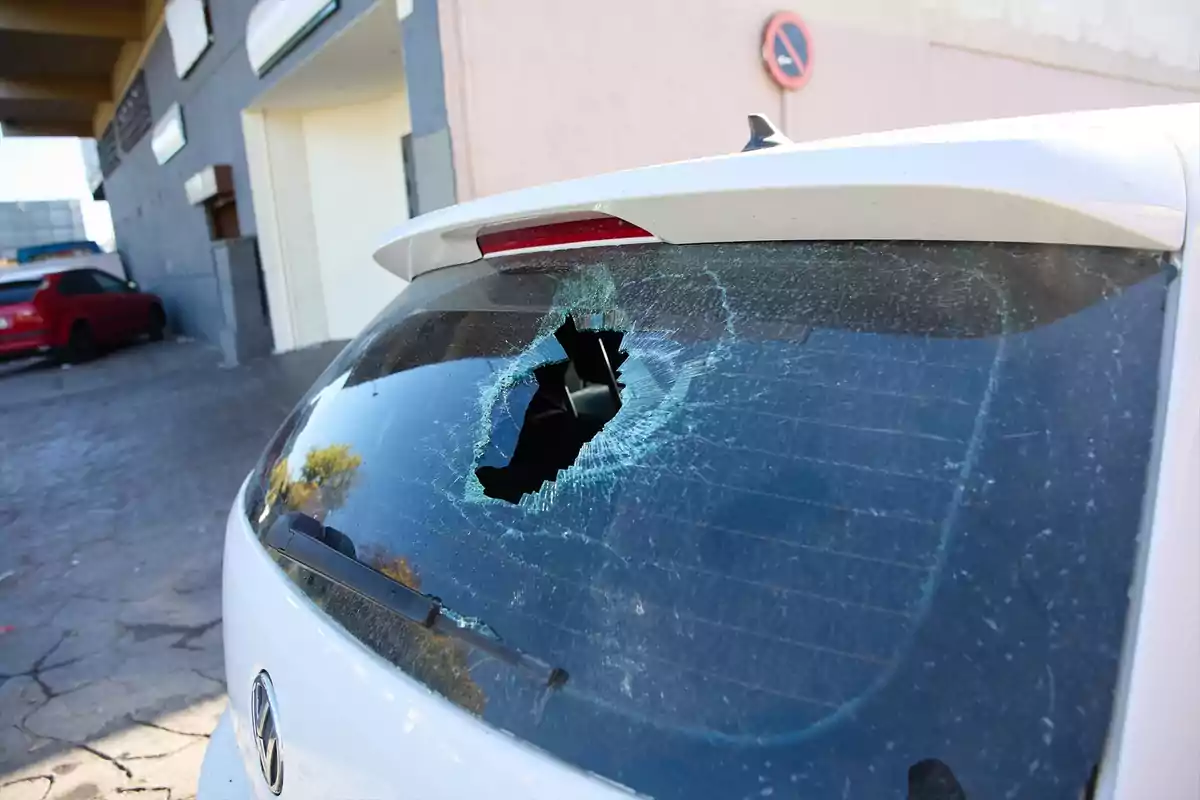 Auto blanco con el medallón trasero roto estacionado junto a una banqueta Auto blanco con el medallón trasero roto estacionado junto a una banqueta