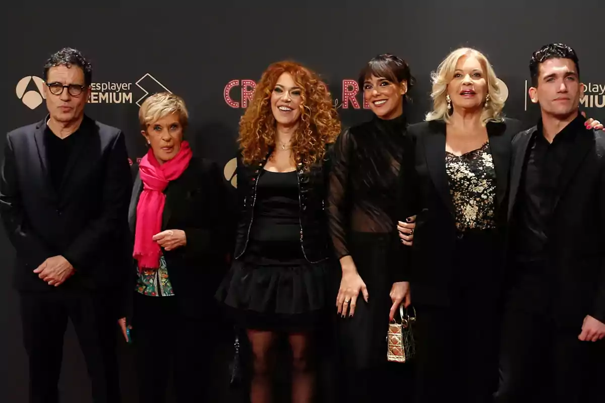 Seis personas posan sonrientes en una alfombra roja con fondo oscuro y logotipos de un evento Seis personas posan sonrientes en una alfombra roja con fondo oscuro y logotipos de un evento