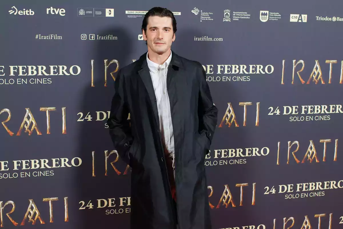 Un hombre posando frente a un cartel promocional de la película 