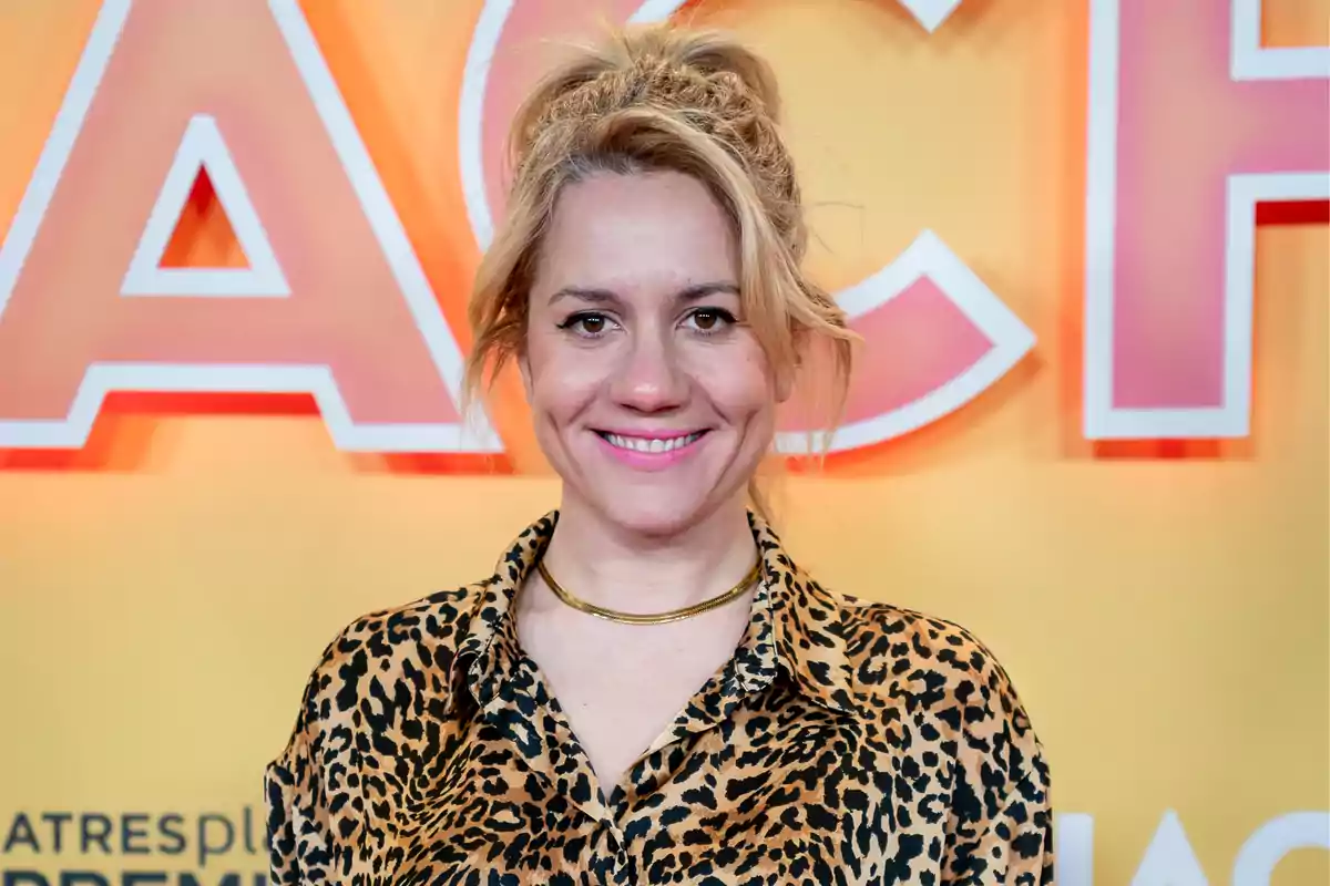 Una persona sonriente con camisa de estampado animal frente a un fondo colorido.