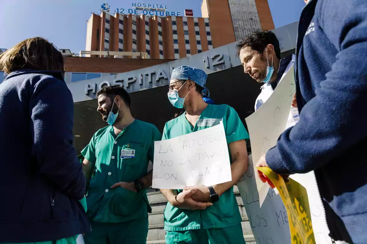 Personal sanitario con mascarillas y uniformes verdes sostiene carteles de protesta frente a la entrada del Hospital 12 de Octubre en Madrid Personal sanitario con mascarillas y uniformes verdes sostiene carteles de protesta frente a la entrada del Hospital 12 de Octubre en Madrid