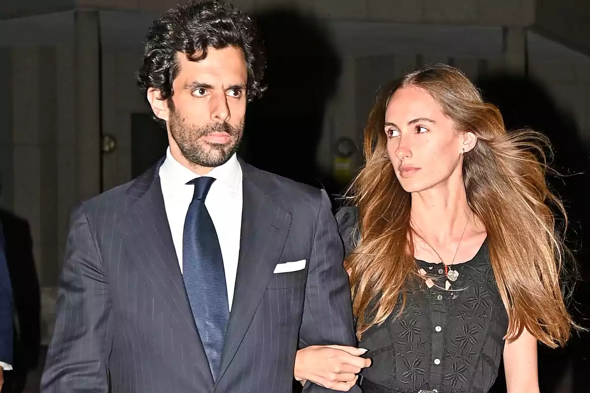 Una pareja caminando de noche con ropa elegante.