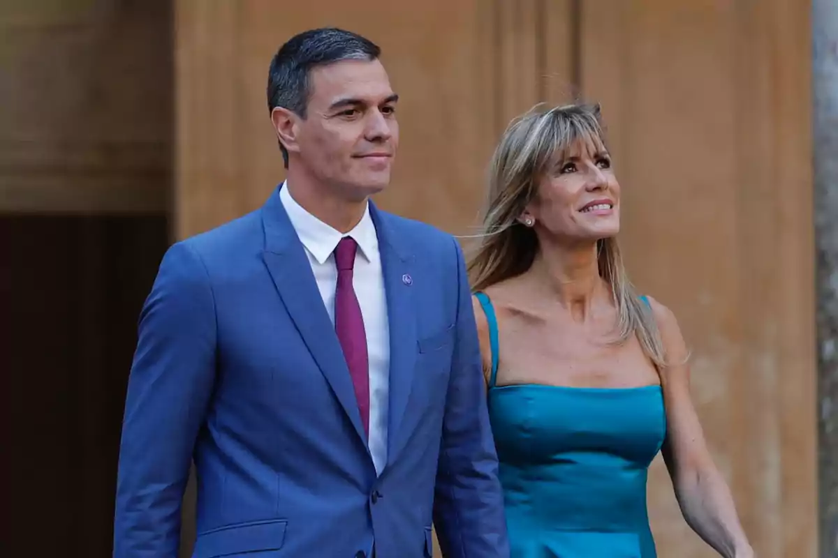 Una pareja elegantemente vestida camina junta sonriendo.