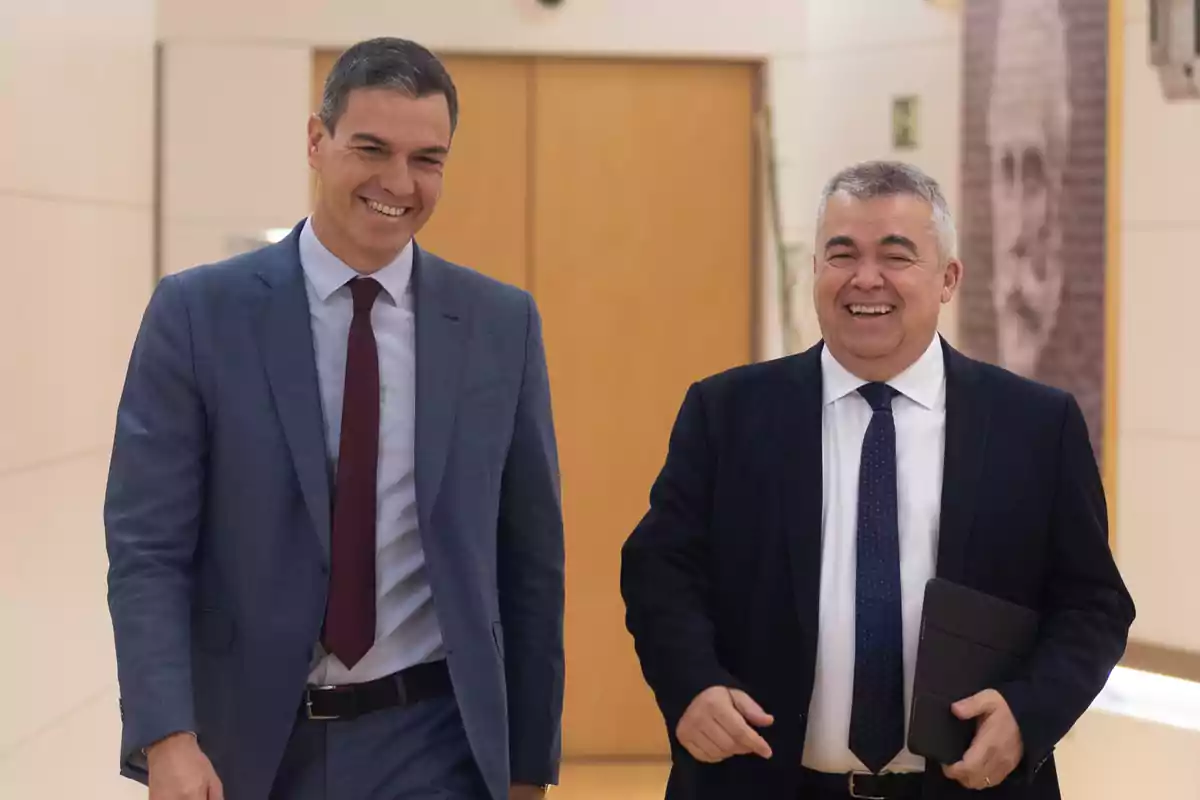 Dos hombres con traje caminan sonrientes por un pasillo iluminado Dos hombres con traje caminan sonrientes por un pasillo iluminado