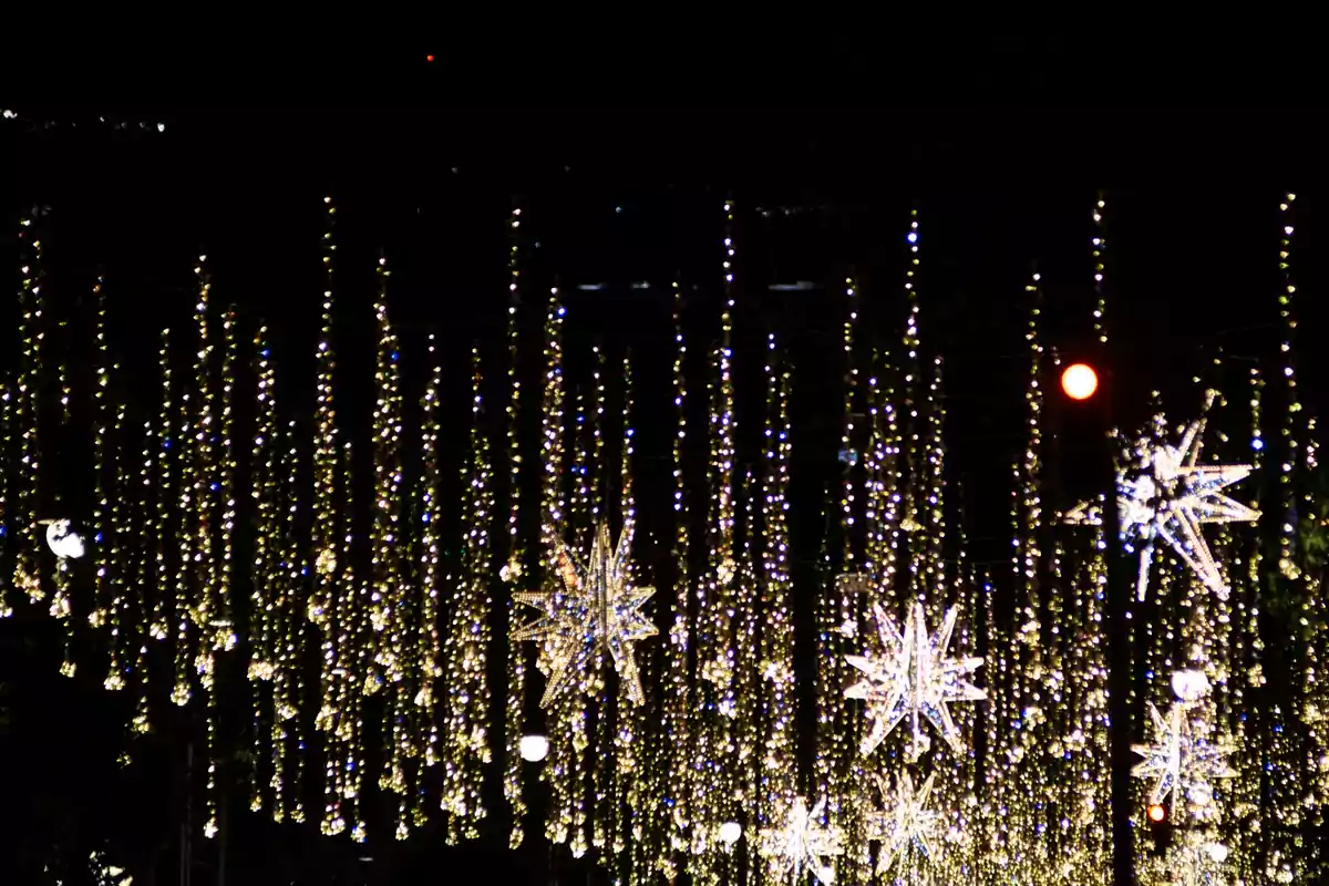 Luces colgantes brillantes en la noche con estrellas decorativas iluminadas.